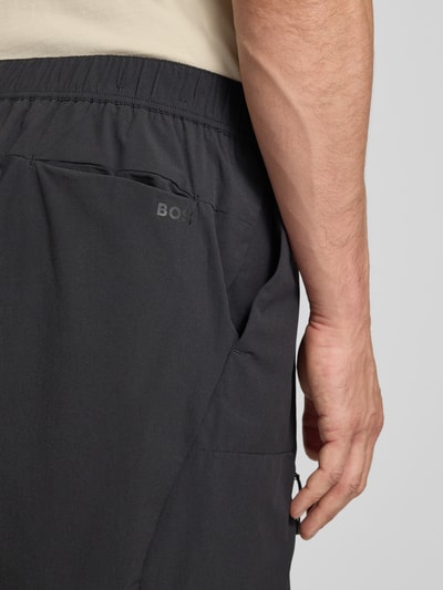 Männermodel trägt Relaxed Fit Cargoshorts mit Label-Schriftzug Modell 'GLOBE CARGO' von BOSS Green, unifarben, Detailaufnahme Rückansicht