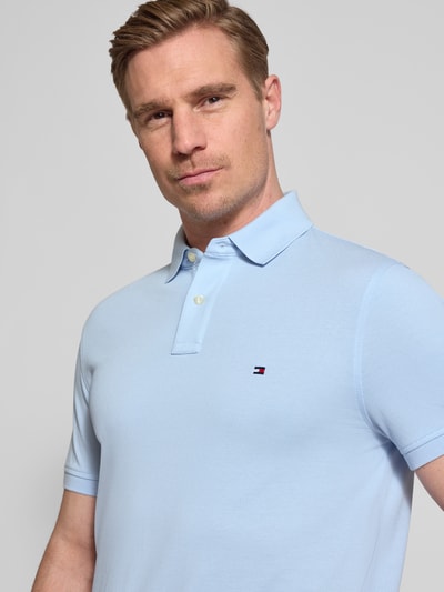 Männermodel trägt Regular Fit Poloshirt aus Baumwoll-Mix von Tommy Hilfiger, Optik: Unifarben, Logo-Stitching, Nahaufnahme Oberkörper.