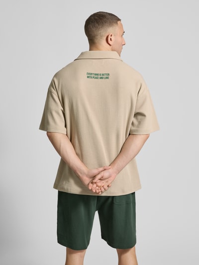 Männermodel trägt Regular Fit Poloshirt mit Logo-Detail von ANOTHER COTTON LAB, beigefarbener Baumwoll-Mix, Strukturmuster, Rückansicht.