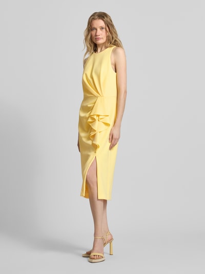Modelka kobieca nosi Cocktailkleid mit Volants od Adrianna Papell, żółty materiał z falbanami, krój prosty, długość midi, widok z przodu całej sylwetki.
