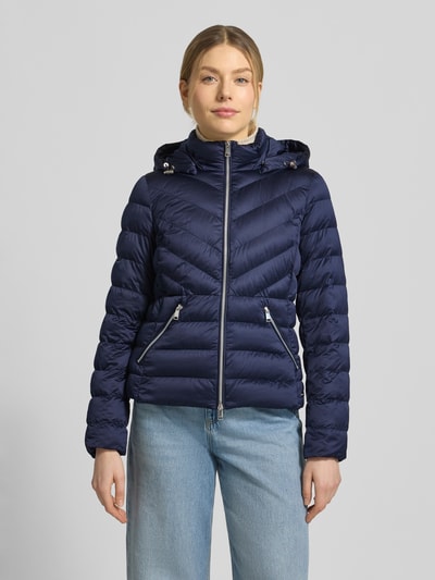 Frauenmodel trägt taillierte Steppjacke mit Zweiwege-Reißverschluss Modell 'ANYA' von Beaumont Amsterdam in Dunkelblau, Ganzkörperansicht von vorne. Kapuze mit Tunnelzug, gestepptes Material, silberne Zipper, Damenjacke; Rückenlänge, Schulterbreite, Brustweite und Ärmellänge orientieren sich an Größe 36.