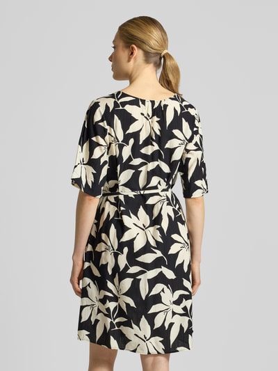 Frauenmodel trägt Relaxed Fix Freizeitkleid aus Viskose-Mix von s.Oliver RED LABEL mit Optik:Allover-Muster, Passform: Relaxed-Fit, Mini-Länge, V-Ausschnitt, Taillengürtel, Ärmelform: Kurzarm, Materialverarbeitung: Crinkle, Ganzkörperansicht Rückansicht.