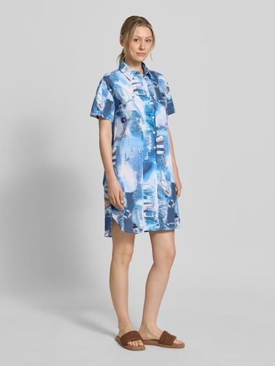 Vrouwenmodel draagt Relaxed Fit Hemdblusenkleid met all-over fotoprint van Marc Cain in blauw-witte tinten, puur katoen, platte kraag, knoopsluiting, met korte mouwen, ruglengte maat 36: 94 cm, borstwijdte 56 cm, mouwlengte 18 cm, geheelopname voorkant.