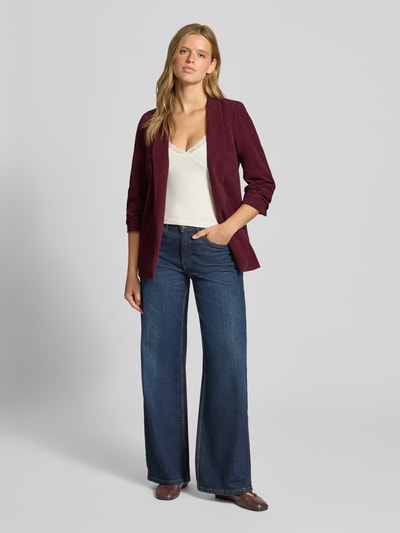 Frauenmodel trägt taillierten Kurzblazer mit 3/4-Arm Modell 'BOSELLA' von PIECES in dunklem Rot, kombiniert mit Jeans, Ganzkörperansicht von vorne.