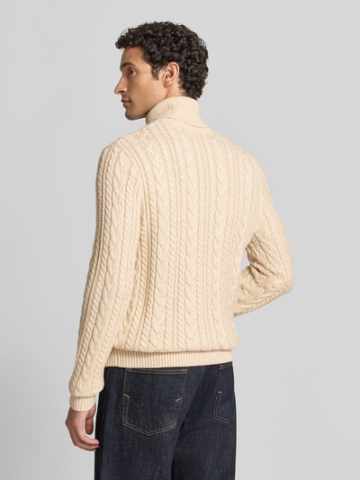 Mężczyzna nosi Slim Fit Strickpullover mit Baumwoll-Anteil Modell 'Callum' von JACK & JONES Premium, beżowy, wzór warkoczowy, długi rękaw, prążkowany golf i ściągacze, materiał o mieszanej fakturze, widok całej sylwetki z tyłu.