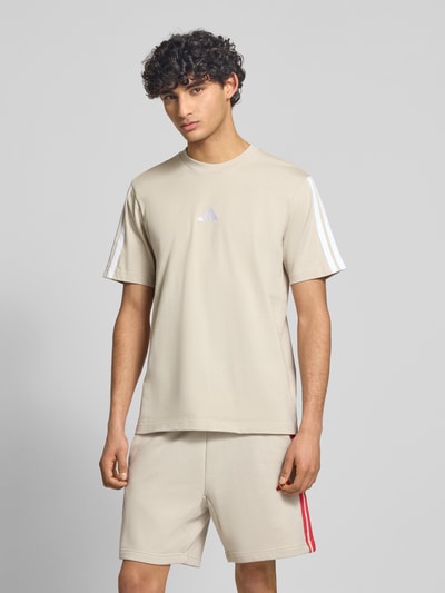 Männermodel trägt Regular Fit T-Shirt aus reiner Baumwolle von adidas Sportswear, Optik: Unifarben, Logo-Print, Kontraststreifen, Rundhals, Kurzarm, Ganzkörperansicht von vorne.