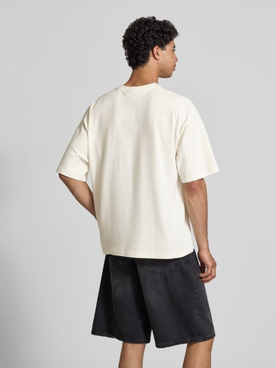Männermodel trägt Relaxed Fit T-Shirt mit Logo-Print von REVIEW in creme, Reine Baumwolle, Rundhalsausschnitt, Halbarm, Rückenlänge 68 cm, Ganzkörperansicht Rückansicht.