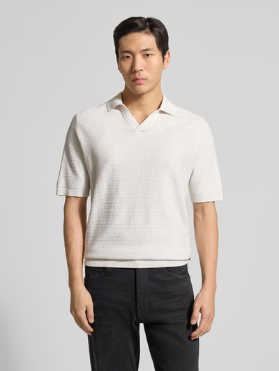 Männermodel trägt Regular Fit Poloshirt aus reiner Baumwolle von Tom Tailor in Strickoptik mit Strukturmuster, Logo-Patch, V-Ausschnitt, kurzarm, gerippte Abschlüsse, Ganzkörperansicht von vorne.