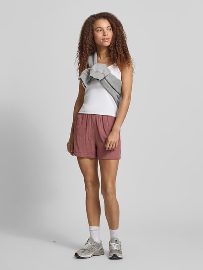 Modelka kobieta nosi Relaxed Fit Shorts aus reiner Baumwolle Modell 'THYRA' od Only, kolor jednolity, materiał krepa bawełniana, boczne kieszenie, elastyczny pas, widok całej sylwetki z przodu.