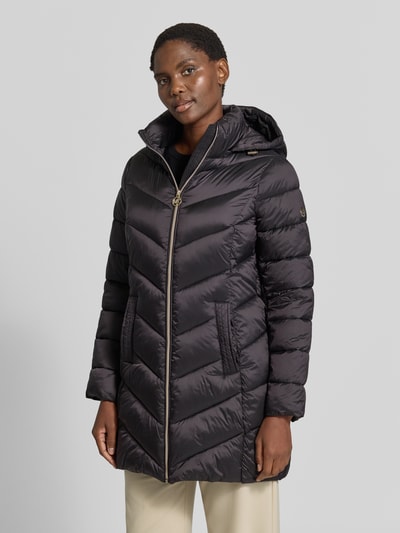 Vrouwenmodel draagt zwarte gewatteerde mantel met capuchon en ritssluiting, Steppmantel mit Kapuze und Reißverschlusstaschen von MICHAEL Michael Kors, recht model, zij-ritszakken, opstaande kraag, ruglengte maat S 86 cm, schouderbreedte 43 cm, borstwijdte 50 cm, mouwlengte 62 cm, Ganzkörperansicht van voren.