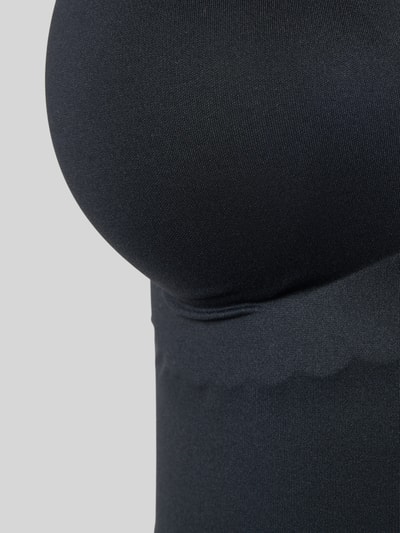 Frauenmodel trägt Unterhemd mit Wellensaum und herausnehmbaren Pads von Skiny, schwarzer Material-Mix mit Stretch-Anteil, Nahaufnahme Oberkörper.