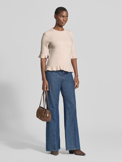 Frauenmodel trägt Longsleeve mit Viskose-Anteil von MORE & MORE in Beige, körpernahe Passform, Strick-Optik, Rüschenbesatz, Ganzkörperansicht von vorne.