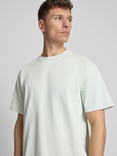 Męski model nosi Oversized T-Shirt mit Rundhalsausschnitt von Lindbergh z bawełny, krój oversized, okrągły dekolt, detal z logo; długość tyłu w rozmiarze M: 70 cm. Nahaufnahme Oberkörper.