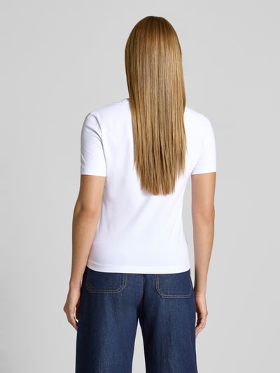 Frauenmodel trägt T-Shirt mit Strasssteinbesatz Modell 'SIENA' von Guess, weiß, Baumwoll-Mix, gerader Schnitt, Ganzkörperansicht Rückansicht.