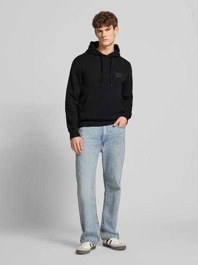 Männermodel trägt Hoodie mit Label-Print und Känguru-Tasche von Jack & Jones, Baumwoll-Mix, Regular Fit, Ganzkörperansicht von vorne.