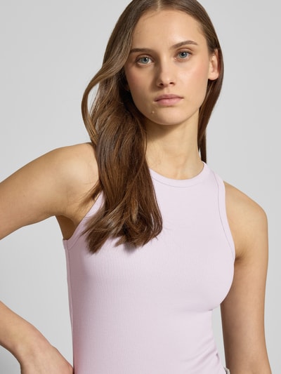 Frauenmodel trägt Tanktop in Ripp-Optik von REVIEW in zartem Rosa, Baumwoll-Elasthan-Mix, eng anliegende Passform, Nahaufnahme Oberkörper.