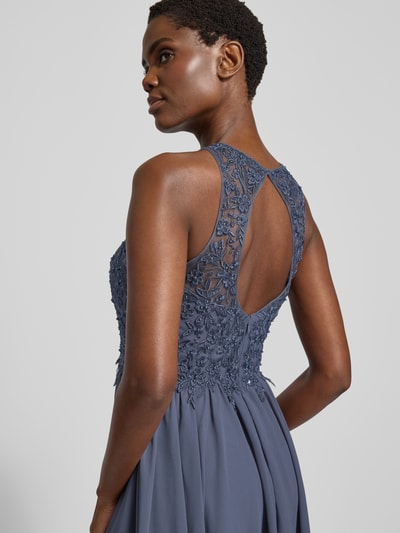Modelka kobieca nosi Cocktailkleid mit floralen Stickereien und Ziersteinen von LAONA w granatowym kolorze, koronkowa tekstura, szerokie ramiączka, ozdobne kamienie, wycięcie na plecach, dwuwarstwowa spódnica, widok na górę sukienki i plecy, zbliżenie na górną część sylwetki.