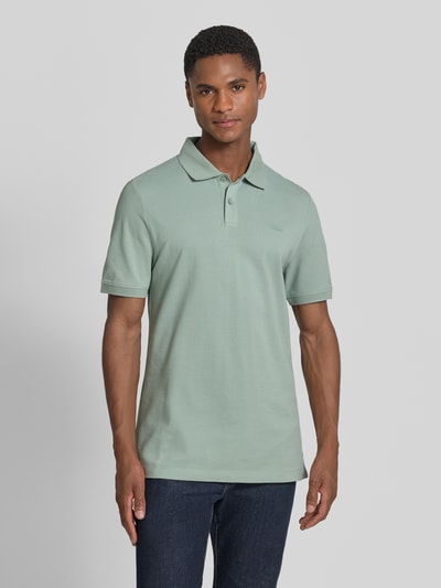 Męski model nosi Regular Fit Poloshirt aus reiner Baumwolle von s.Oliver RED LABEL, bawełniany pikowany materiał, krótki rękaw, jednolita zieleń, widok z przodu, całe ciało.