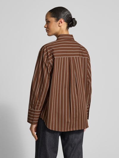 Frauenmodel trägt Relaxed Fit Hemdbluse mit Brusttasche Modell 'LLAMA' von Mango, braun mit weißen Streifen, reine Baumwolle, Ganzkörperansicht Rückansicht.
