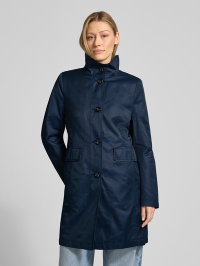 Modelka kobieca nosi Krótki płaszcz z stójką i kieszeniami z patką od Gil Bret, mieszanka bawełny, krój slim fit, listwa guzikowa, kolor ciemnogranatowy, gładka tekstura, długość tyłu w rozmiarze 36: 86 cm, szerokość ramion: 39 cm, szerokość w rozmiarze 36: 46 cm, długość rękawów: 65 cm. Zdjęcie całej sylwetki z przodu.