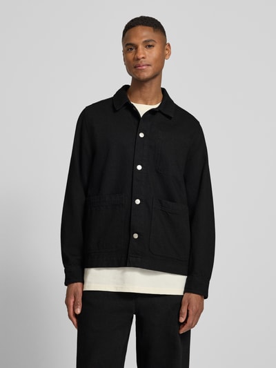 Männermodel trägt Regular Fit Overshirt mit Brusttasche Modell 'Layton' von Les Deux, Reine Baumwolle, Kentkragen, Knopfleiste, Eingrifftaschen, Sportmanschetten, schwarze Farbe, glatte Textur, Ganzkörperansicht von vorne.