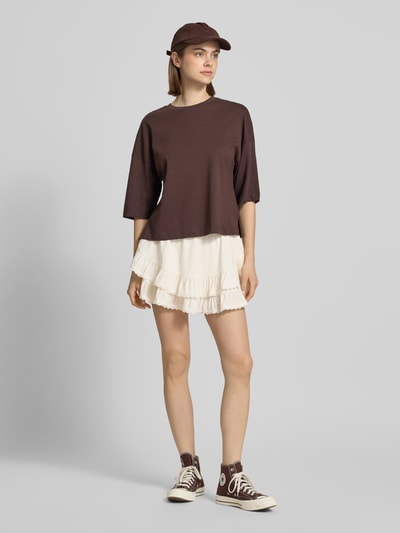 Frauenmodel trägt Minirock aus Viskose-Mix mit Volantsaum Modell 'Frill' von Gina Tricot, cremefarben, A-Linie, elastischer Bund, Damen, Bundweite 35 cm, Gesamtlänge 33 cm, Nahaufnahme Oberkörper.