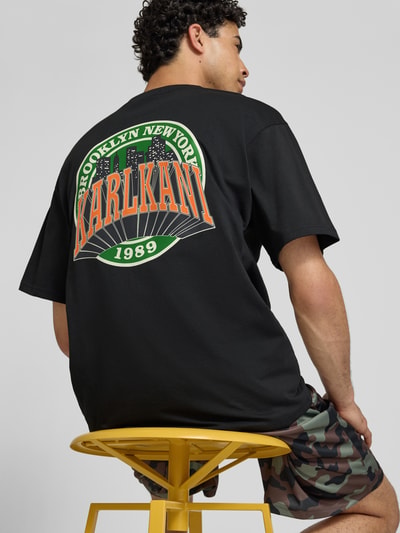 Männermodel trägt Oversized T-Shirt mit Logo-Stitching von KARL KANI in Schwarz, Reine Baumwolle, Oversized-Fit, Rundhalsausschnitt, Rückenlänge bei Größe M 72 cm, Ganzkörperansicht Rückansicht.