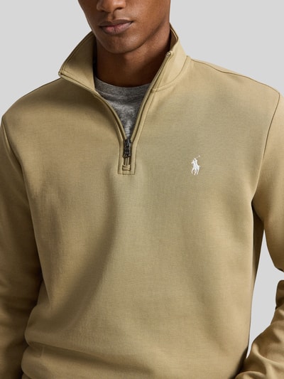 Männermodel trägt Relaxed Fit Troyer aus Baumwoll-Mix von Polo Ralph Lauren in Beige mit Zipper, glatte Textur, Nahaufnahme Oberkörper. Herren Troyer von Polo Ralph Lauren
