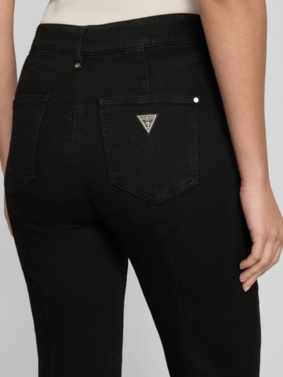 Frauenmodel trägt High Waist Palazzo Jeans mit seitlichen Knöpfen von GUESS, Baumwoll-Mix mit Stretch, Detailaufnahme Rückansicht. Modell 'NEW FAYE', Bundweite 38 cm, Innenbeinlänge 81 cm.