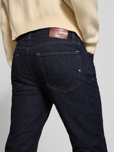 Männermodel trägt Slim Fit Jeans mit Raw-Denim-Optik von PEPE JEANS in dunkler Waschung, 5-Pocket-Design, Rückansicht Nahaufnahme.