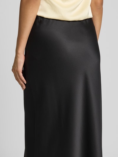 Frauenmodel trägt Ausgestellter Maxi-Rock mit elastischem Bund Modell 'MERLE' von VERO MODA, glänzender schwarzer Stoff, Nahaufnahme Oberkörper.