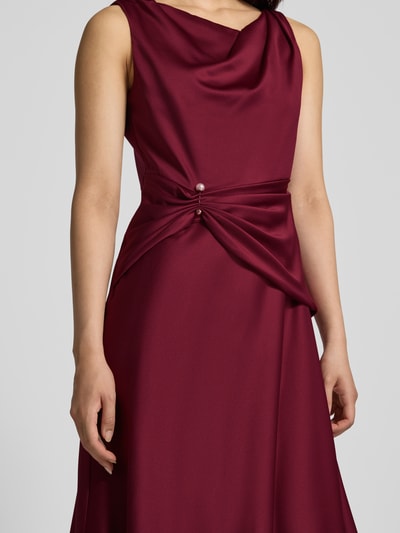 Frauenmodel trägt Cocktailkleid aus Satin mit Raffungen von Adrianna Papell in dunklem Rot, taillierte Passform, Nahaufnahme Oberkörper.