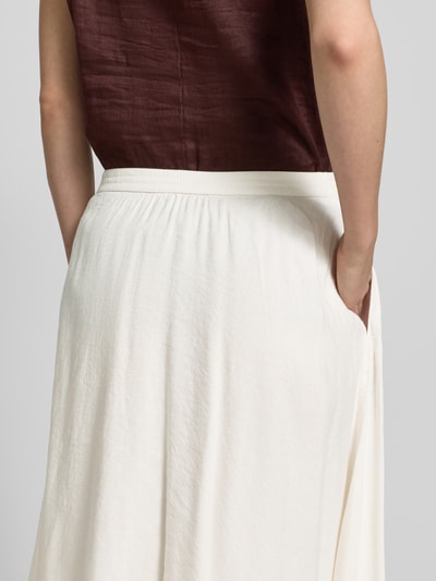 Frauenmodel trägt Midi-Rock aus reinem Leinen von Tommy Hilfiger in Creme, ausgestellt mit elastischem Bund und Fransen, Nahaufnahme Rückansicht.