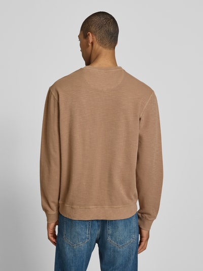 Männermodel trägt Regular Fit Sweatshirt mit Rundhalsausschnitt von Scotch & Soda in beige aus katoenmix mit labeldetail, ruglengte maat M 68 cm, mouwlengte maat M 65 cm, ganzlichaamsaanzicht van achteren.