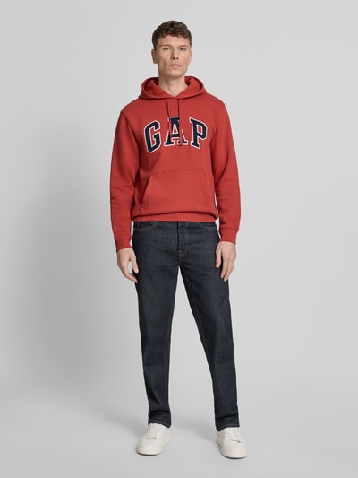 Mannelijk model draagt Hoodie met Kängurutasche van GAP in rood, katoenmix, loose fit, kangoeroezak, labelstiksel, geribde boorden, met capuchon en trekkoord, ruglengte maat M 69 cm, mouwlengte maat M 65 cm, geheel vooraanzicht.
