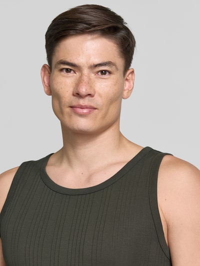 Männermodel trägt Regular Fit Tank Top aus Baumwoll-Mix Modell 'ANDRE' von SELECTED HOMME, olivgrün, gestreifte Struktur, Nahaufnahme Oberkörper.