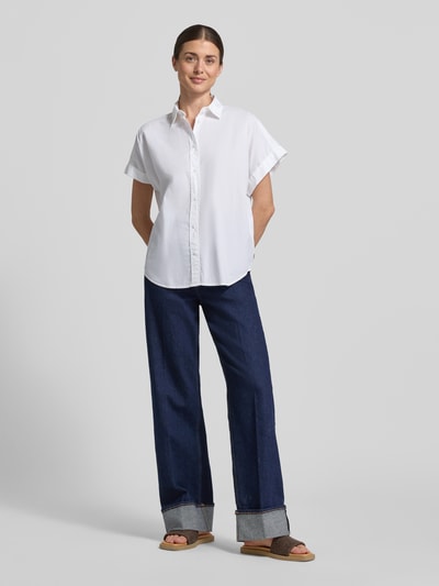 Frauenmodel trägt Regular Fit Hemdbluse mit Hemdblusenkragen Modell 'Isabel' von ECOALF in Weiß, reine Baumwolle, Kurzärmelig, durchgehende Knopfleiste, Rückenlänge 74 cm, Ärmellänge 16 cm, Ganzkörperansicht von vorne.