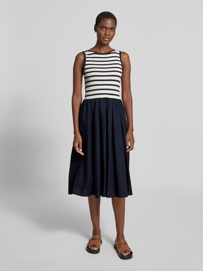 Frauenmodel trägt Midikleid mit Rundhalsausschnitt und Eingrifftasche von Gant, A-Linie, Feinripp, dunkelblau und weiß, Ganzkörperansicht von vorne.