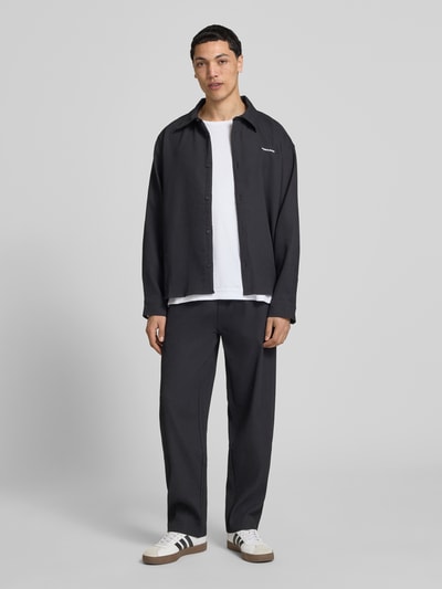 Männermodel trägt Sweatpants mit Strukturmuster und elastischem Bund von Pegador in Schwarz, Material-Mix mit Stretch-Anteil, Relaxed-Fit, Ganzkörperansicht von vorne