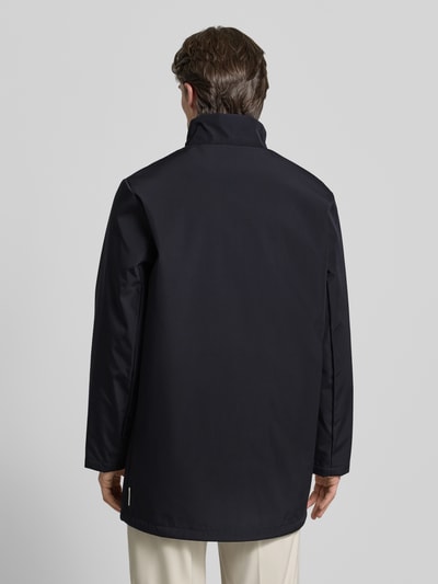 Männermodel trägt Trenchcoat mit Stehkragen von ARMANI EXCHANGE in Dunkelblau, gerader Schnitt, Rückenansicht Ganzkörperansicht.