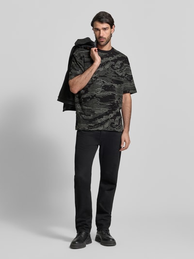Männermodel trägt Regular Fit T-Shirt aus reiner Baumwolle Modell 'TE_WILDNATURE' von BOSS Orange, abstraktes Allover-Muster, Ganzkörperansicht von vorne.