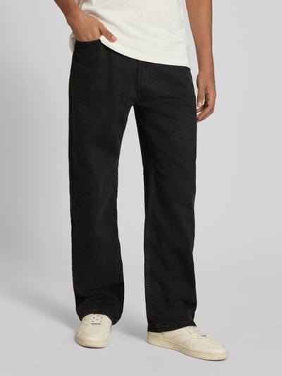 Męski model nosi Baggy Fit Jeans mit Knopfverschluss od REVIEW, czarne jeansy, 5 kieszeni, szerokość w rozmiarze 32: 41 cm, długość wewnętrzna nogawki: 77 cm, zdjęcie całej sylwetki z przodu.