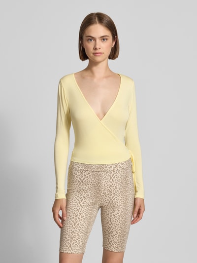 Frauenmodel trägt Cardigan in Wickel-Optik Modell 'Luca' von OH APRIL in Gelb, V-Ausschnitt, schmale Form, Ganzkörperansicht von vorne. Modal-Elasthan-Mix, Rückenlänge 46 cm bei Größe S.