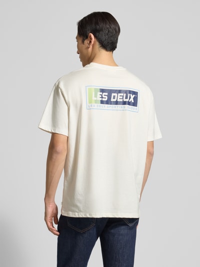 Męski model nosi T-Shirt mit Logo-Print Modell 'Chase' von Les Deux z czystej bawełny, prosty krój, nadruk z logo, widok całej sylwetki z tyłu