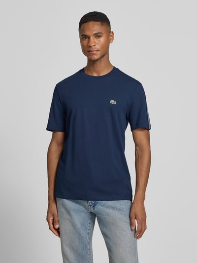 Męski model nosi Regular Fit T-Shirt aus reiner Baumwolle von Lacoste, kolor granatowy, krój regular fit, label-tape, dekolt okrągły, krótki rękaw, bawełna, jednolita faktura, widok na całe ciało z przodu.