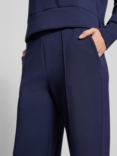 Kobiece modelka nosi Sweatpants mit elastischem Bund od Christian Berg Woman, ciemnogranatowe, materiał z dodatkiem modalu, luźny krój, kieszenie boczne i tylne, zbliżenie na biodra i talię, detailaufnahme.