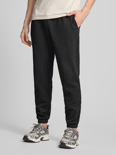 Męski model nosi Sweatpants mit Logo und elastischem Bund od GAP z mieszanki bawełny, krój regular fit, ciemny kolor, długość wewnętrzna nogawki 78 cm, Ganzkörperansicht z przodu.