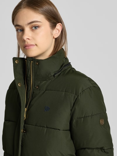 Vrouwenmodel draagt Regular Fit Jacke in Stepp-Optik van Superdry in donkergroen met opstaande kraag, stiksels, detailopname bovenlichaam. Ruglengte maat S: 64 cm, schouderbreedte: 49 cm, borstwijdte: 59 cm, mouwlengte: 62 cm.