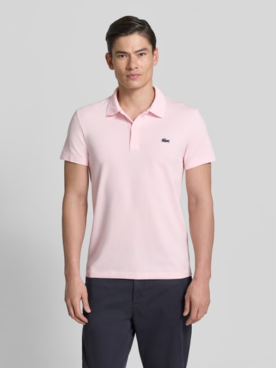 Männermodel trägt Regular Fit Poloshirt aus Baumwoll-Mix von Lacoste, Optik: Unifarben, Logo-Patch, Polokragen, Kurzarm, Ganzkörperansicht von vorne.