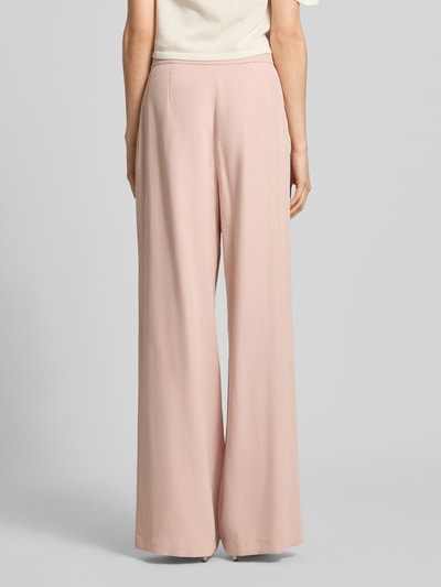Frauenmodel trägt Bundfaltenhose aus Viskose-Mix mit Knopfverschluss von Jake*s Collection in zartem Rosaton, Wide Leg, glatte Textur, Ganzkörperansicht Rückansicht. Bundweite 37 cm, Innenbeinlänge 80 cm, Größe 36.